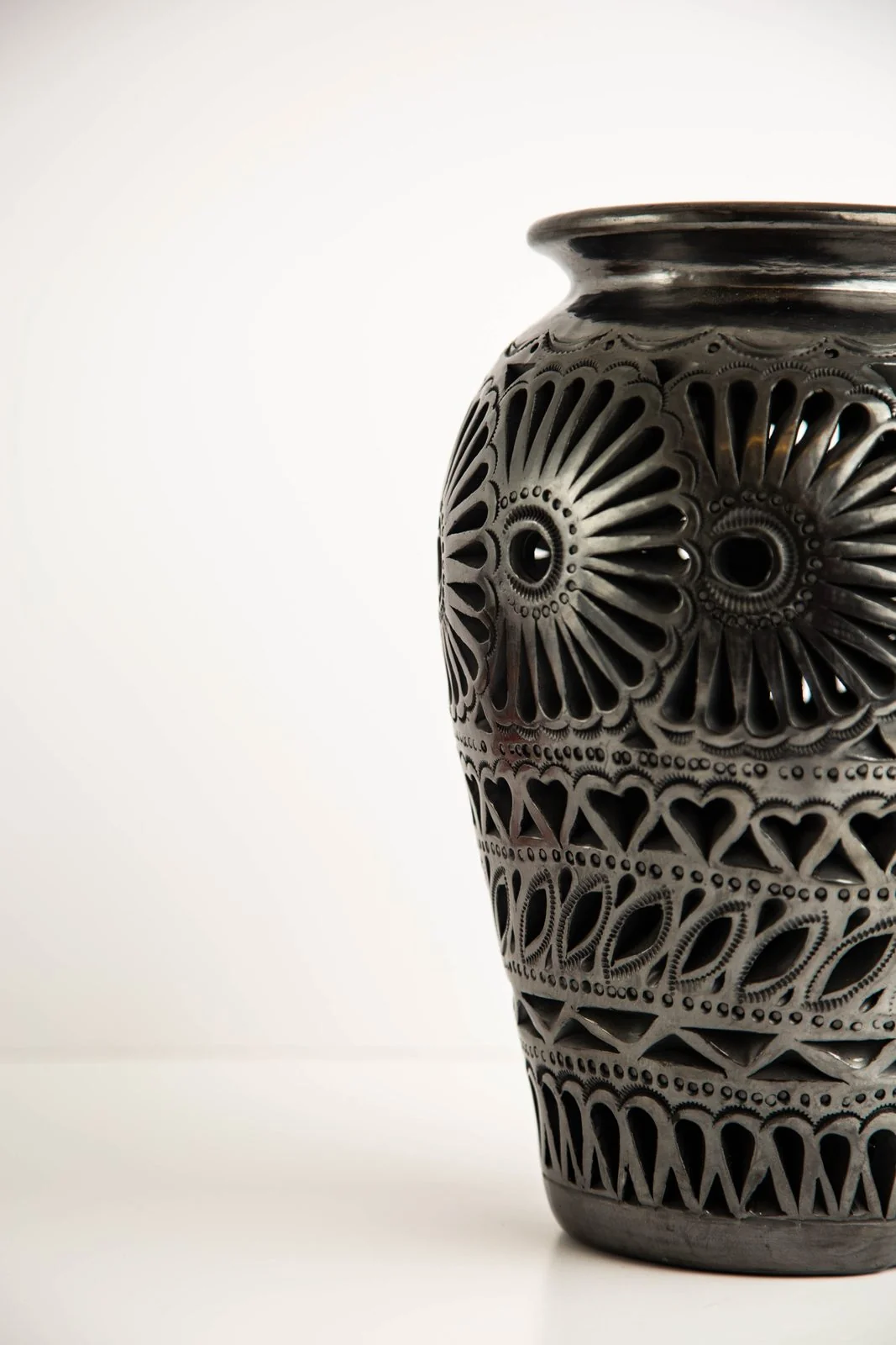 Handmade black clay vase from Oaxaca with intricate cutout floral patterns